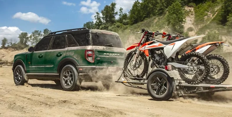 A green 2024 Ford Bronco Sport towing some dirt bikes.