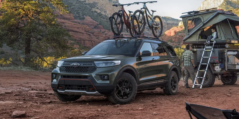 A dark green 2024 Ford Explorer with 2 bikes on the top.